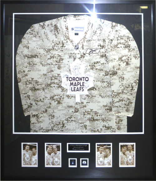 framed hockey jersey in camouflage pattern with toronto maple leafs emblem and player signatures, with photos of hockey players at the bottom